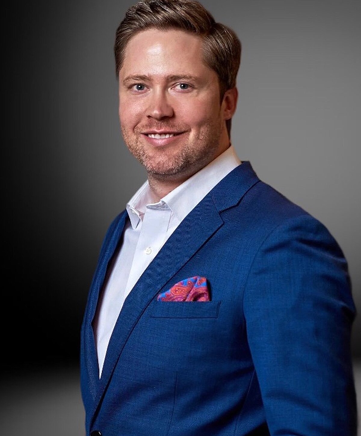 Smiling man in blue suit with pocket square.
