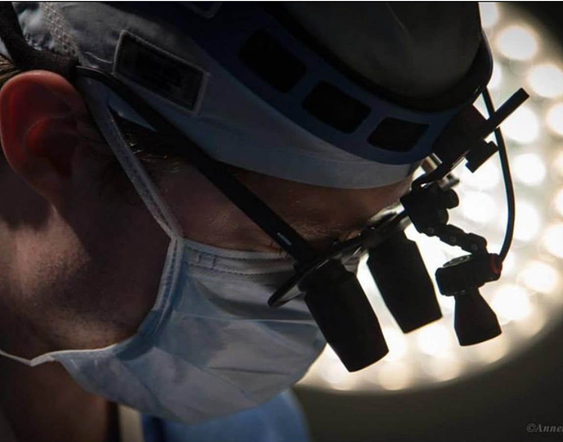 Surgeon focusing under bright operating room lights.