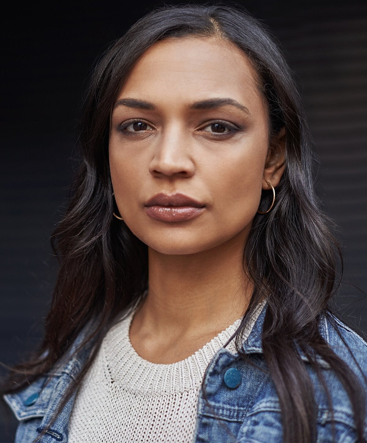Model posing in neutral-colored lingerie against backdrop.