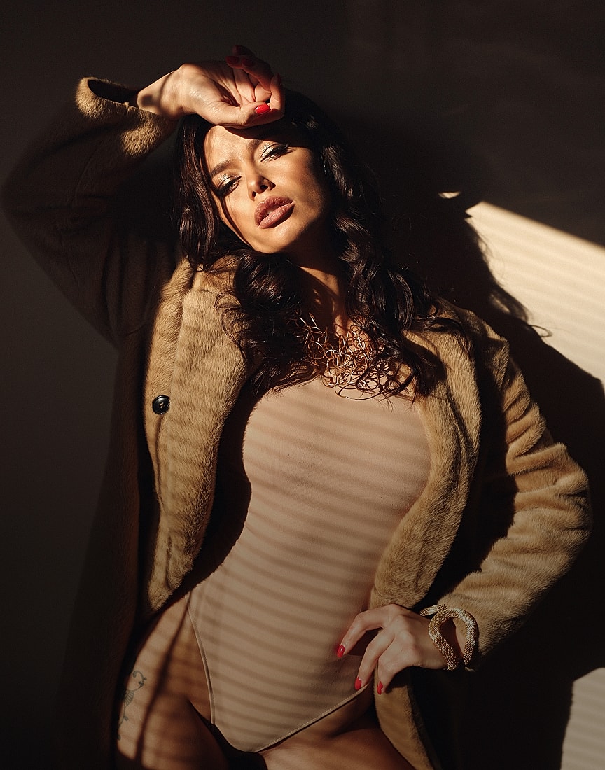 Woman in stylish outfit with dramatic lighting.