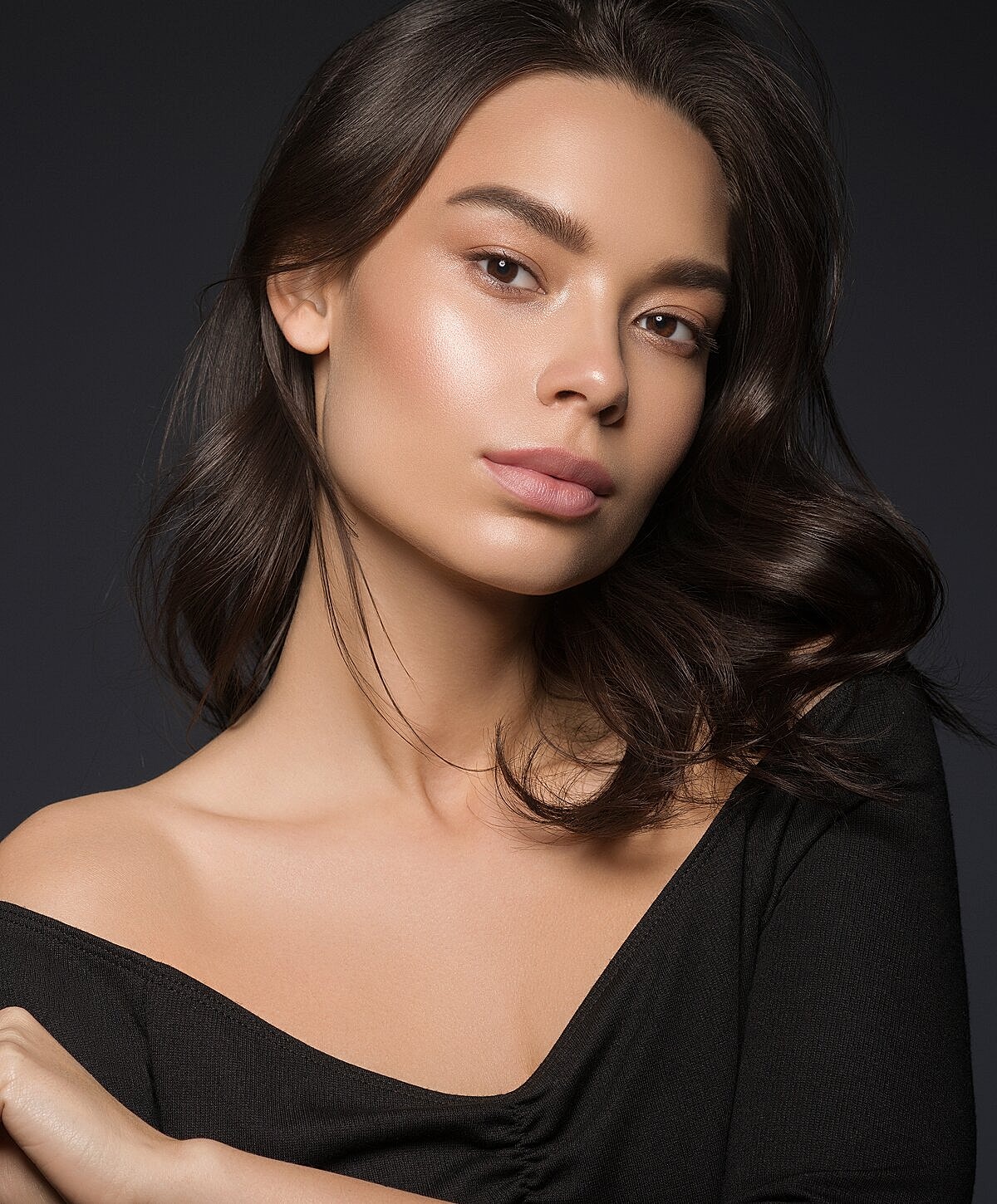 Model posing in neutral-colored lingerie against backdrop.