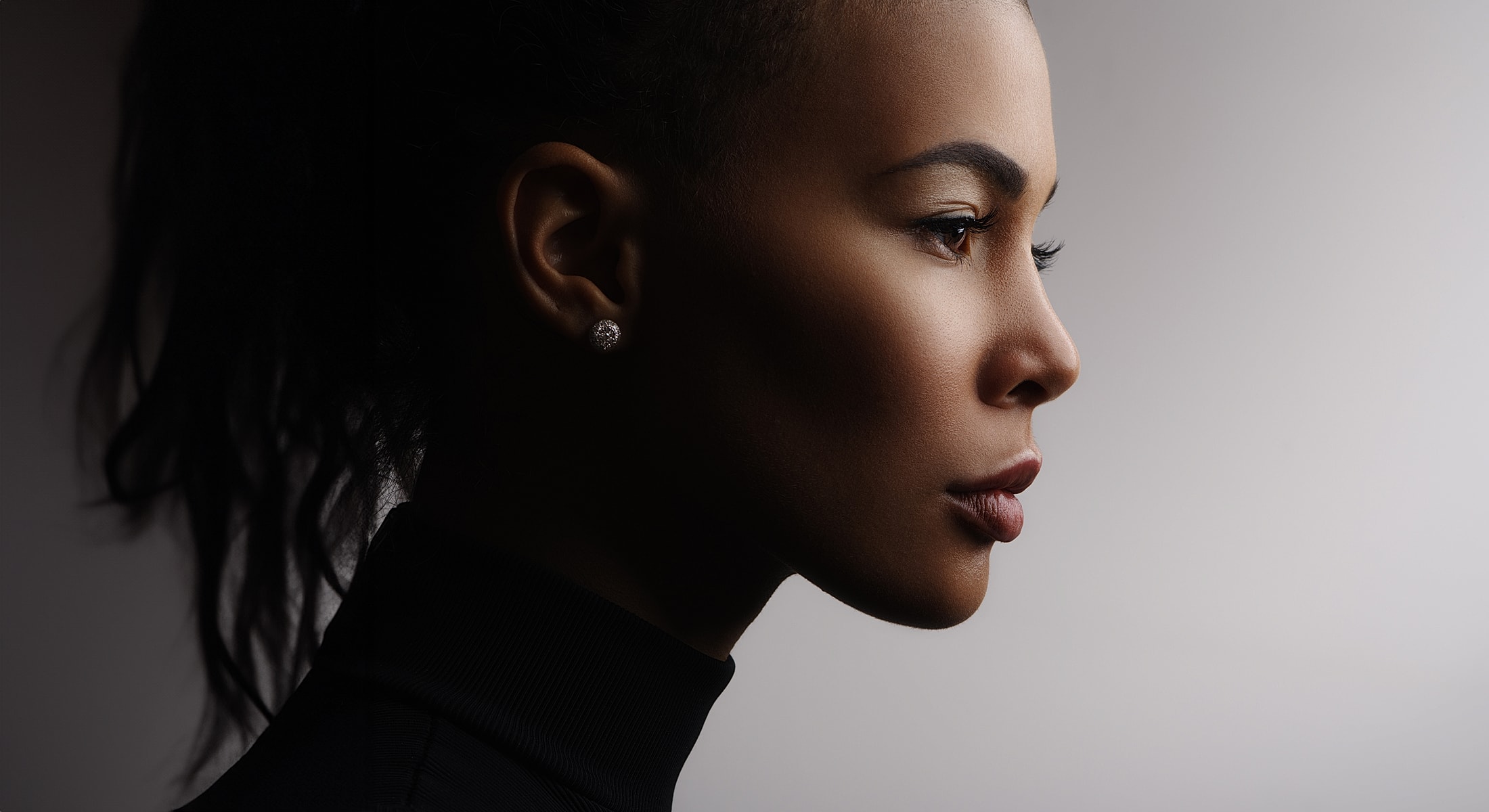 Profile portrait of a woman against a gradient background.