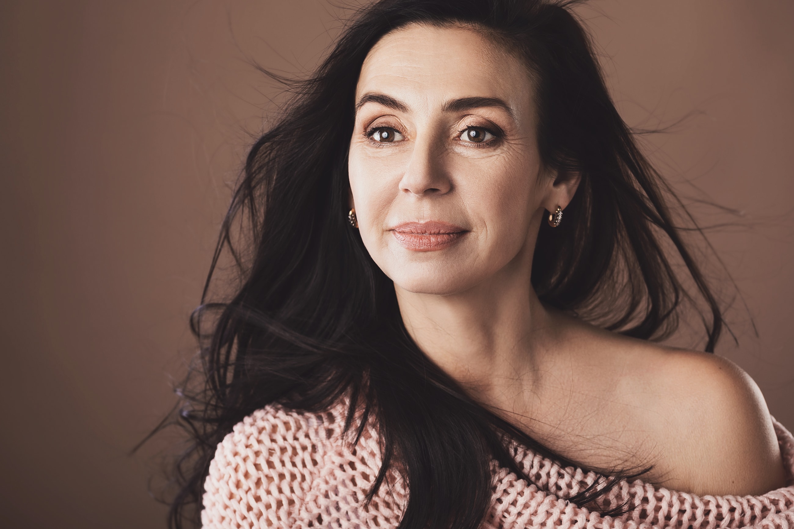 Confident woman with long black hair, thoughtful expression.