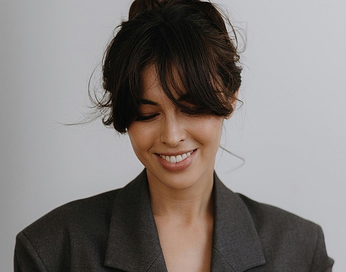 Smiling woman in a grey blazer, soft expression.