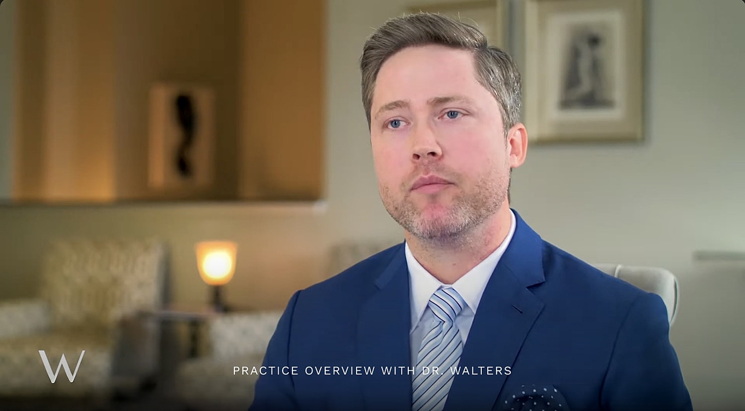 Man in suit discussing practice overview.